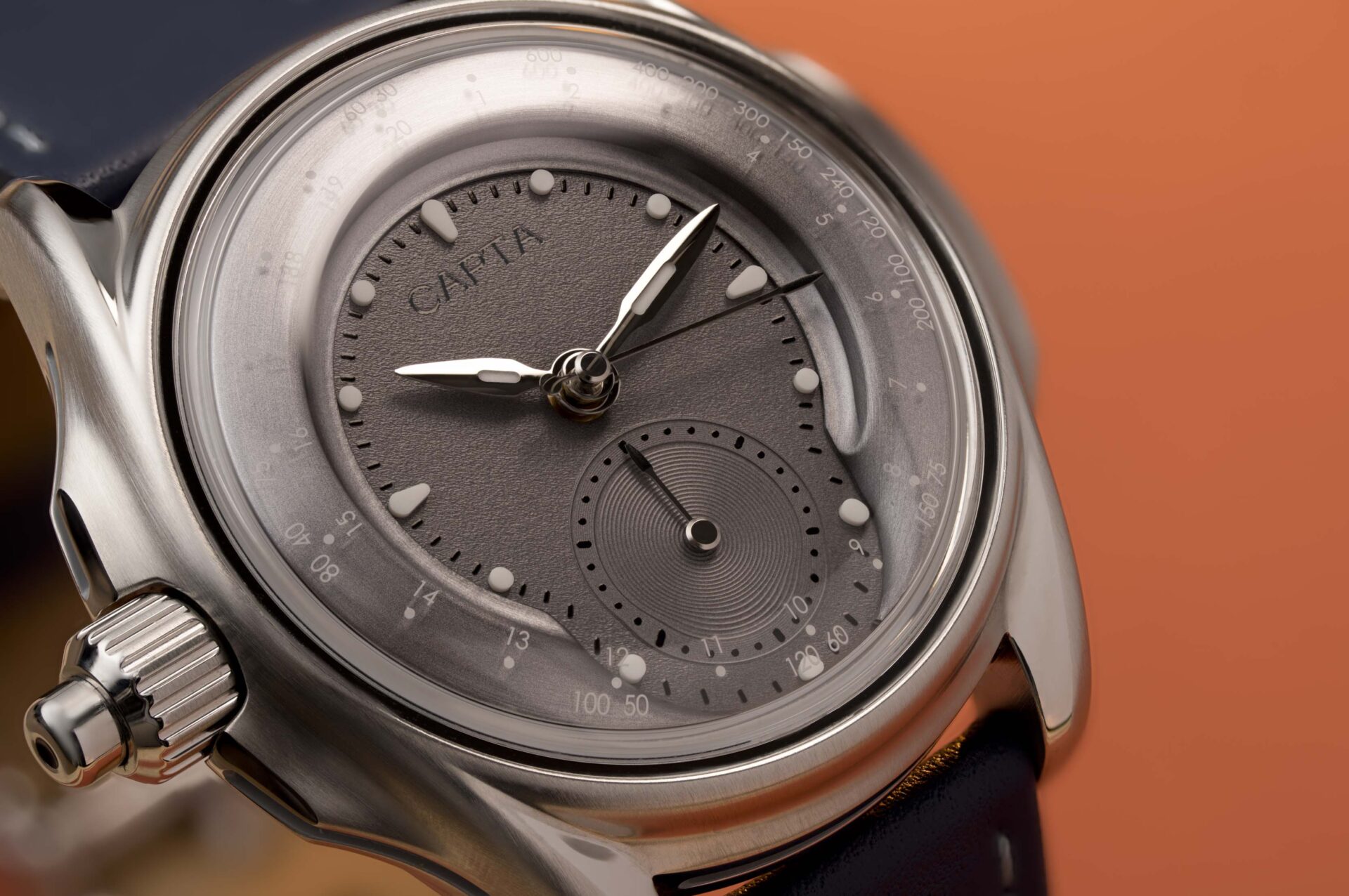 Gros plan sur le cadran Gris Fantôme de la montre française Capta Omnia Uniscale sur fond orange