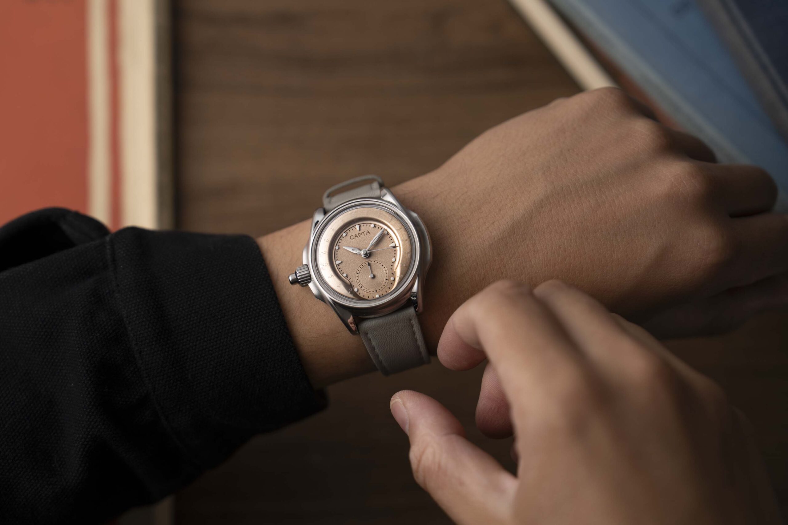 Montre française Capta Omnia Uniscale Sable Bronzé portée au poignet avec une manche noire