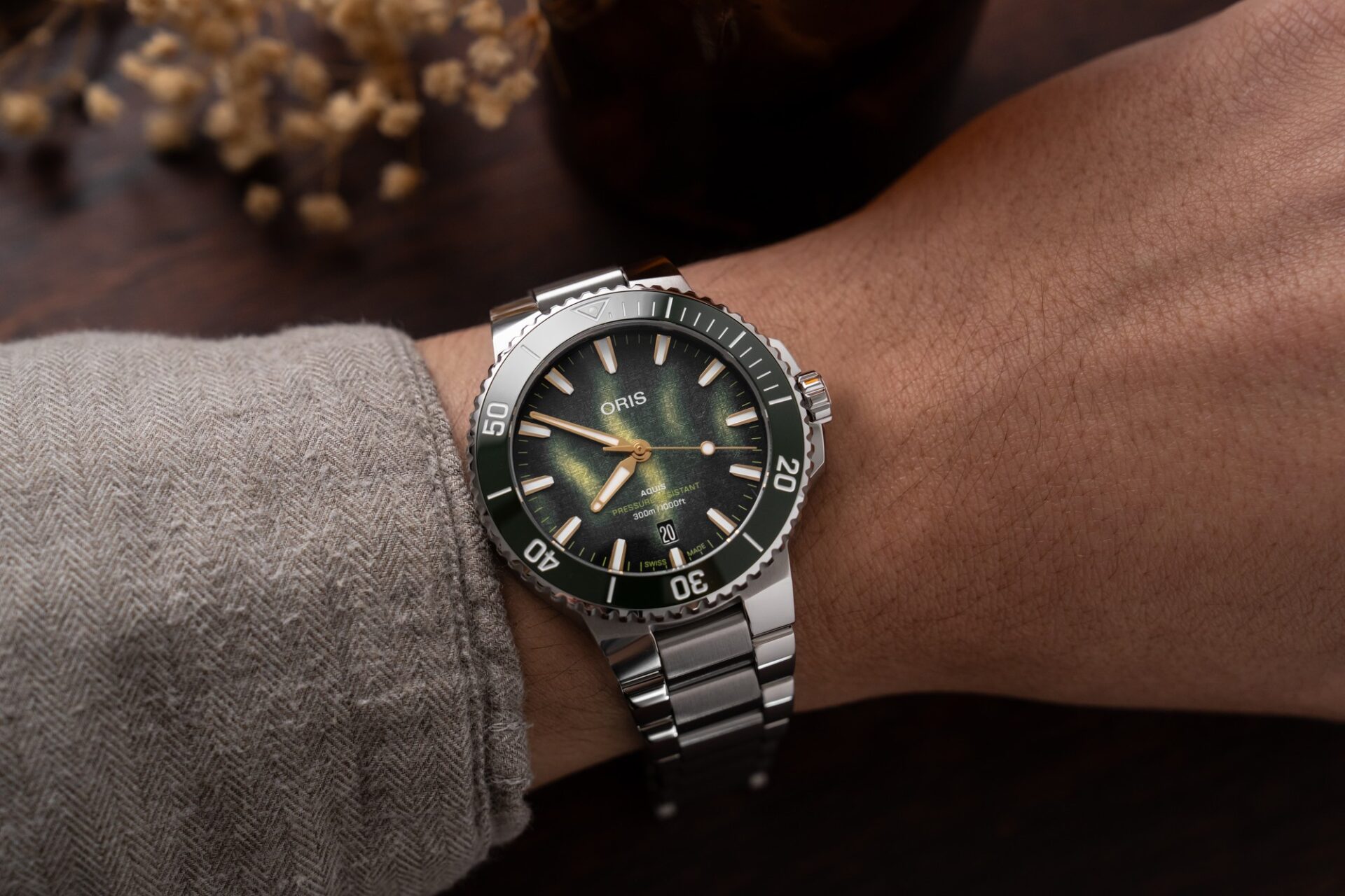 Oris Aquis Kelp Forest Limited Edition portée au poignet avec un pull gris, cadran vert et bracelet acier